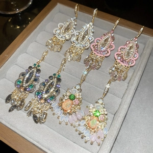 Macro shot of luxury crystal tassel earrings in gold with colorful gems in a velvet tray