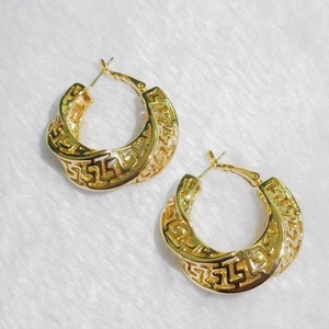 Vintage oversized gold hollow hoop earrings with Greek key pattern on white fur