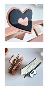 Close-up of heart-shaped hair claw clips in pink, beige, and black-white拼接 designs