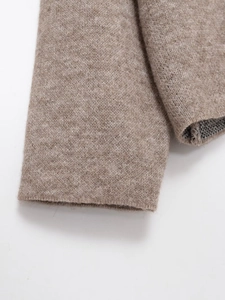 Close-up of ribbed cuffs on beige knitted sweater showing high-quality wool texture