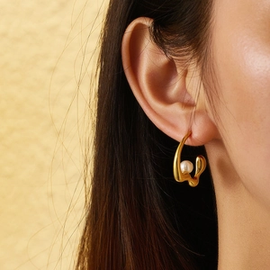 Close-up of elegant gold plated earring with a white pearl on a female model