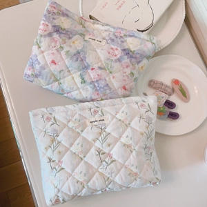 Close-up of quilted floral cosmetic bags with diamond stitching and woven brand labels