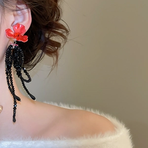Détail de la boucle d'oreille fleur avec pampille noire perlée portée sur modèle