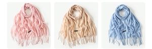 Close-up of fringe details and Cashmere labels on pink, beige and blue scarves