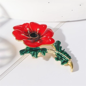 Enamel red flower brooch with green leaves and gold stem on a clean white backdrop