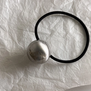 Gros plan d'un chouchou noir minimaliste avec une boule en métal argenté brossé