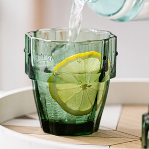 Creative cactus-shaped green glass water cup with lemon slice in natural setting
