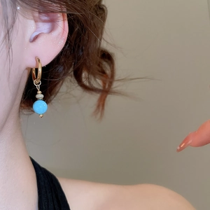 Detail of vintage French gold earrings with turquoise beads worn by a model