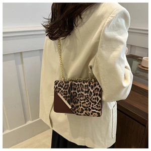 Close-up of leopard print crossbody bag with gold chain strap on a white corduroy coat