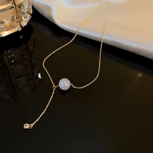 Detail of gold titanium steel necklace with a colorful pearl and y-shaped pendant drop