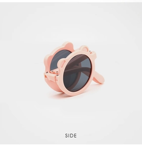 Side view of foldable pink kids sunglasses with cute bear ear design in compact form