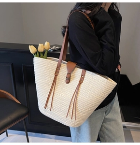 Detailed view of woven straw tote bag with brown leather straps and tulip decor
