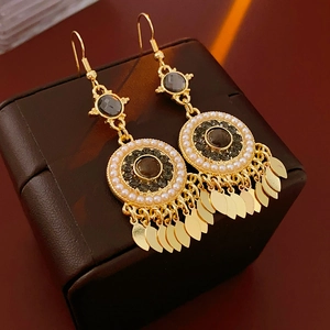 Macro shot of vintage gold tassel earrings with dark gemstones and white pearls detail