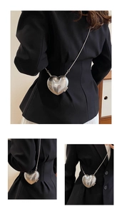 Detail of heart-shaped silver metallic mini bag with sleek chain strap for women