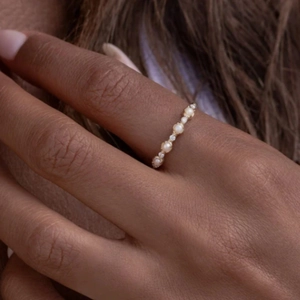 Close-up of minimalist gold ring with pearls and tiny diamonds in a French style design