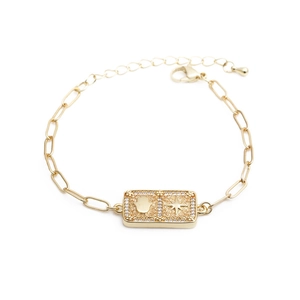 Detail showing gold hamsa hand and polaris paperclip chain bracelet with cz stones