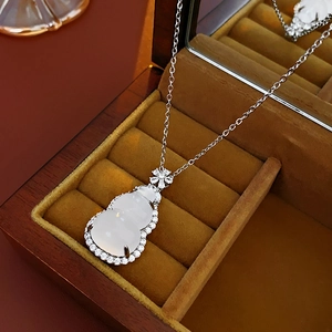 Detailed close-up of a zircon gourd pendant on a silver chain inside a velvet jewelry box