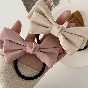 Gedetailleerde close-up van grote fluwelen strik haarelastiekjes in roze en crème beige