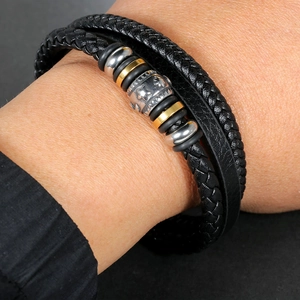Macro shot of a multilayer woven leather bracelet with star-engraved beads and metal rings