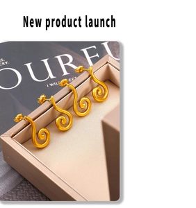 Detail of gold geometric spiral stud earrings in a luxury champagne jewelry box