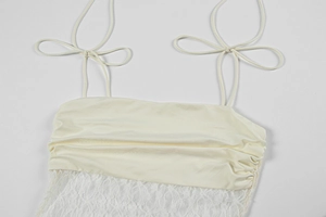 Close-up of cream camisole featuring pleated silk-like fabric and delicate white lace trim