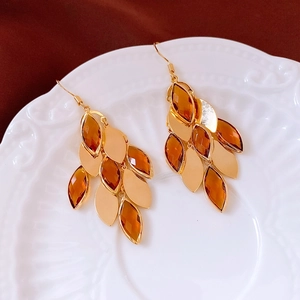 Detail view of vintage leaf-shaped earrings with amber gemstones on a white ceramic dish
