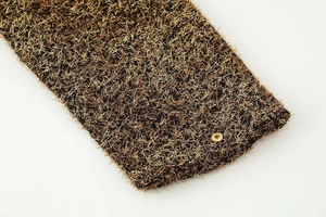 Macro detail of gold metallic thread fabric texture and a polished round metal button