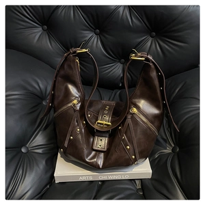 Detail of dark brown vintage hobo bag with golden hardware and motorcycle style accents