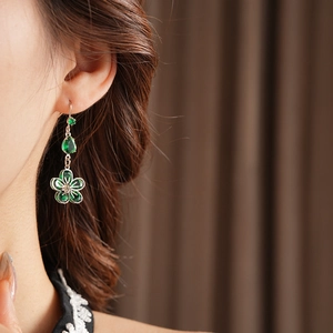 Close-up of elegant flower drop earrings with green zircon stones on model's ear