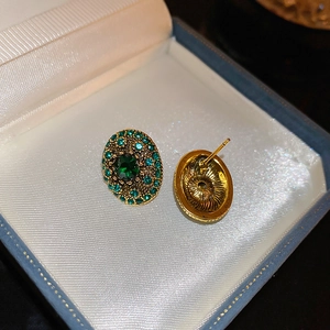 Macro shot of vintage emerald oval stud earrings with gold finish and rhinestone details