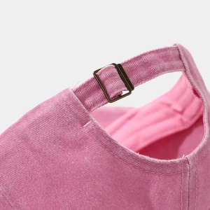 Macro view of pink washed denim cap with adjustable antique bronze metal buckle closure
