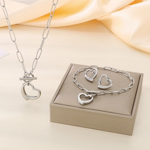 Detailed set of silver heart pendant necklace, bracelet and earrings on silk background