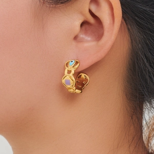 Golden C-shaped stainless steel earrings with evil eye and purple square details on model