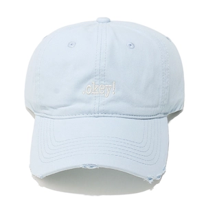 Macro detail of light blue cotton baseball cap featuring white .okey! embroidery and distressed brim