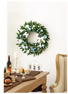 Détail d'une couronne de Noël avec boules bleues et lumières LED sur un mur blanc