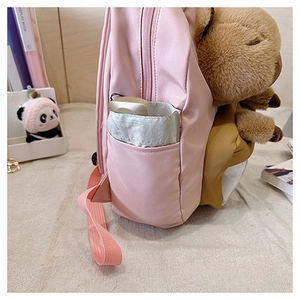 Pink student backpack side view showing side pocket storage and plush animal decoration