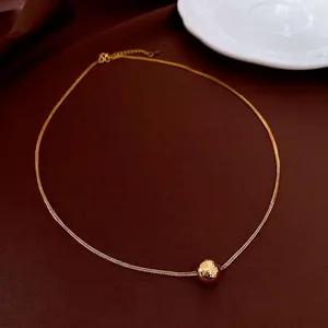 Hammered 18K gold plated bead necklace with delicate chain on a leather surface
