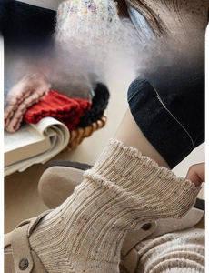 Detailed view of beige speckled wool socks featuring a wide elastic ribbed cuff design