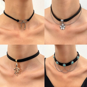 Detailed view of four black choker necklaces with snake, flower and bow pendants