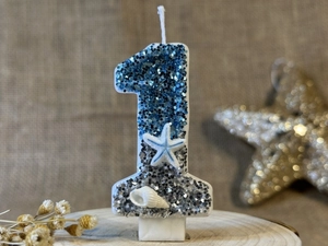 Macro shot of glittery number 1 birthday candle with ocean starfish and seashell ornaments