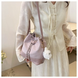 Pink bucket bag with silver chain and plush charm shown on a stylish model