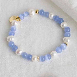 Close-up of glacier blue cat-eye beads and pearls with heart pendant necklace