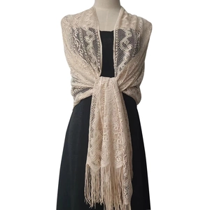 Detailed view of beige lace shawl featuring floral hollow patterns and long fringe tassels