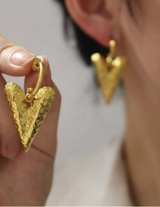Detail of 18K gold plated heart earrings with unique hammered metal texture and glossy finish