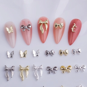Detailed view of silver and gold metal bow nail charms with delicate rhinestones for manicure