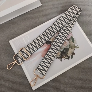 Detail of adjustable black and white woven bag strap with premium gold metal clasps