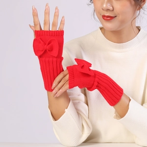 Detail of red cable-knit fingerless gloves featuring a cute bow on the wrist cuffs
