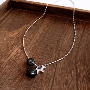 Macro detail of silver bead chain necklace with black beads and horse pendant on wood