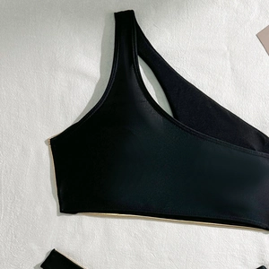 Detail of black one-shoulder bikini top with metallic gold piping and elastic fabric