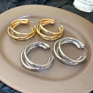 Detailed close-up of layered gold and silver geometric hoop earrings on a luxury tray